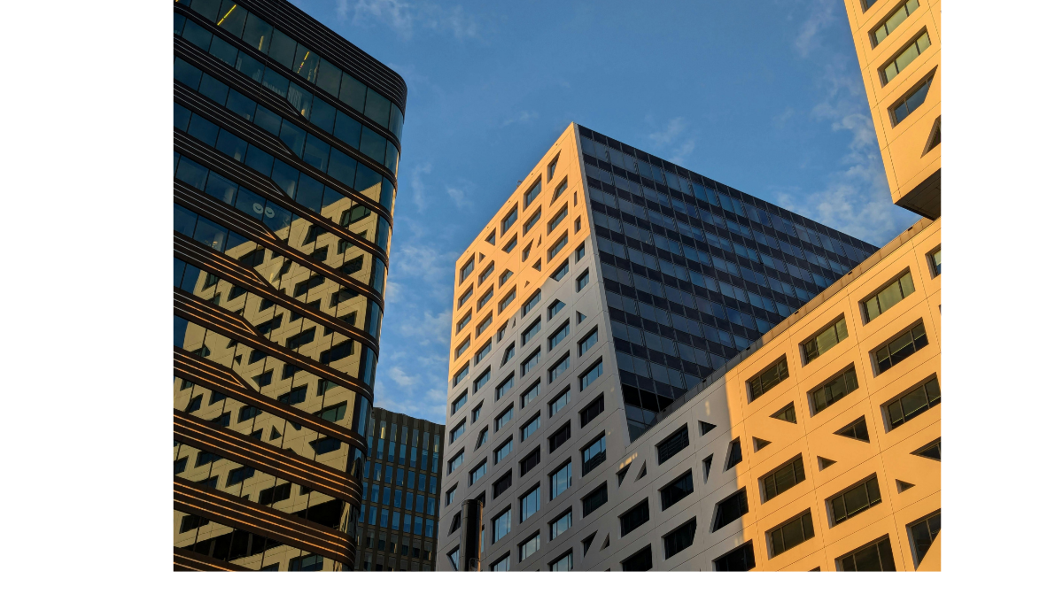 Vue en contre-plongée d’un groupe de bâtiments modernes en centre-ville, comprenant des tours résidentielles ou commerciales aux façades géométriques et vitrées, illustrant l’architecture contemporaine urbaine au Québec.