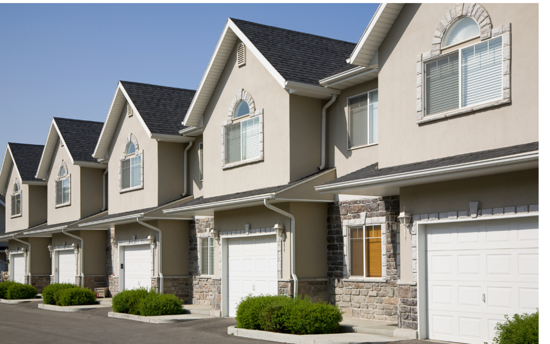 Rangée de maisons de ville modernes avec garages intégrés et façades en pierre, dans un quartier résidentiel
